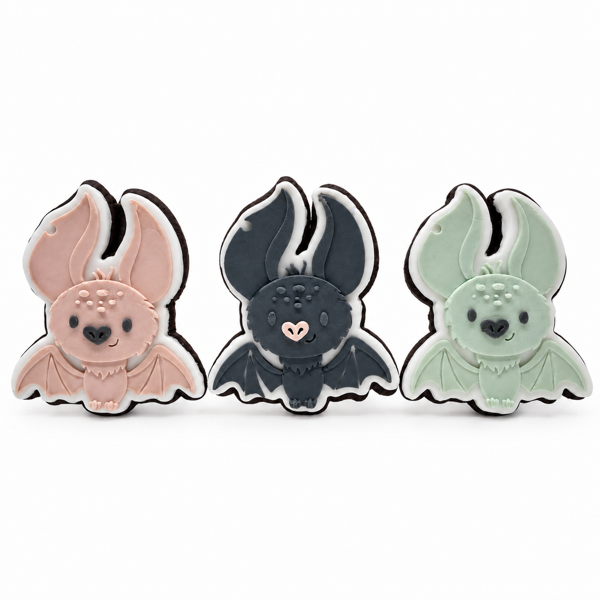 Three Midnight Cocoa bat fondant sugar cookies in blush, charcoal and sage on a white background.